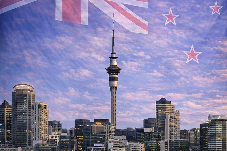 Auckland skyline against a backdrop of the New Zealand flag