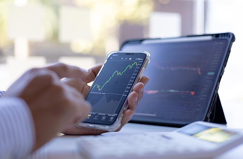 Man checking stock values on mobile phone and tablet