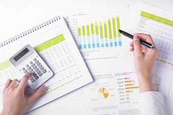 Woman working on her finances, with spreadsheets, graphs and a calculator