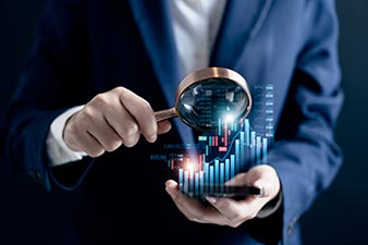 Man examining financial data through a magnifying glass