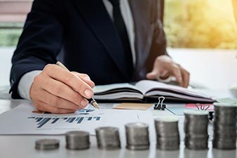 Financial planner with spreadsheets and graphs behind a stack of money